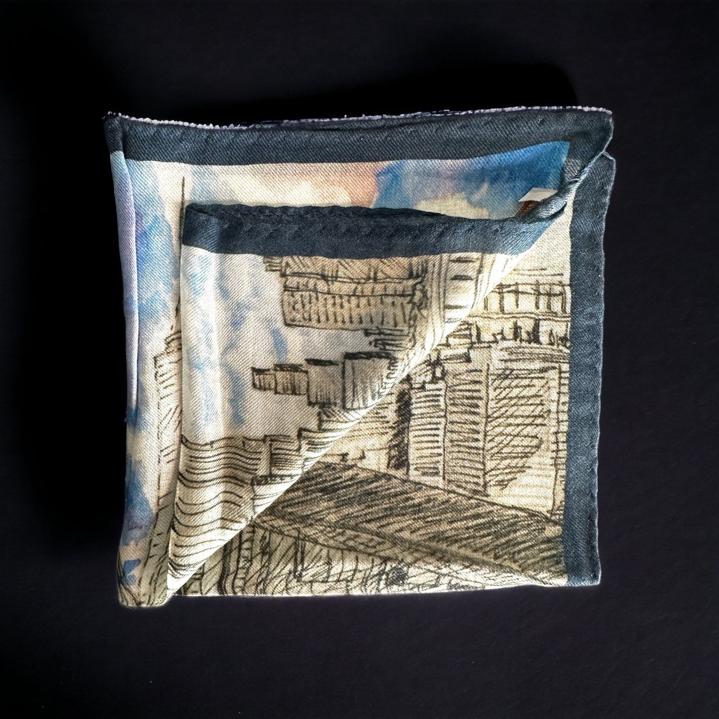 A silk pocket square of the New York City skyline as seen from the Brooklyn Bridge. Nothing more iconic than NYC and here it is shown in a beautiful watercolor and pencil artwork on a silk pocket square complete with a party cloudy sky. Hand rolled edges.