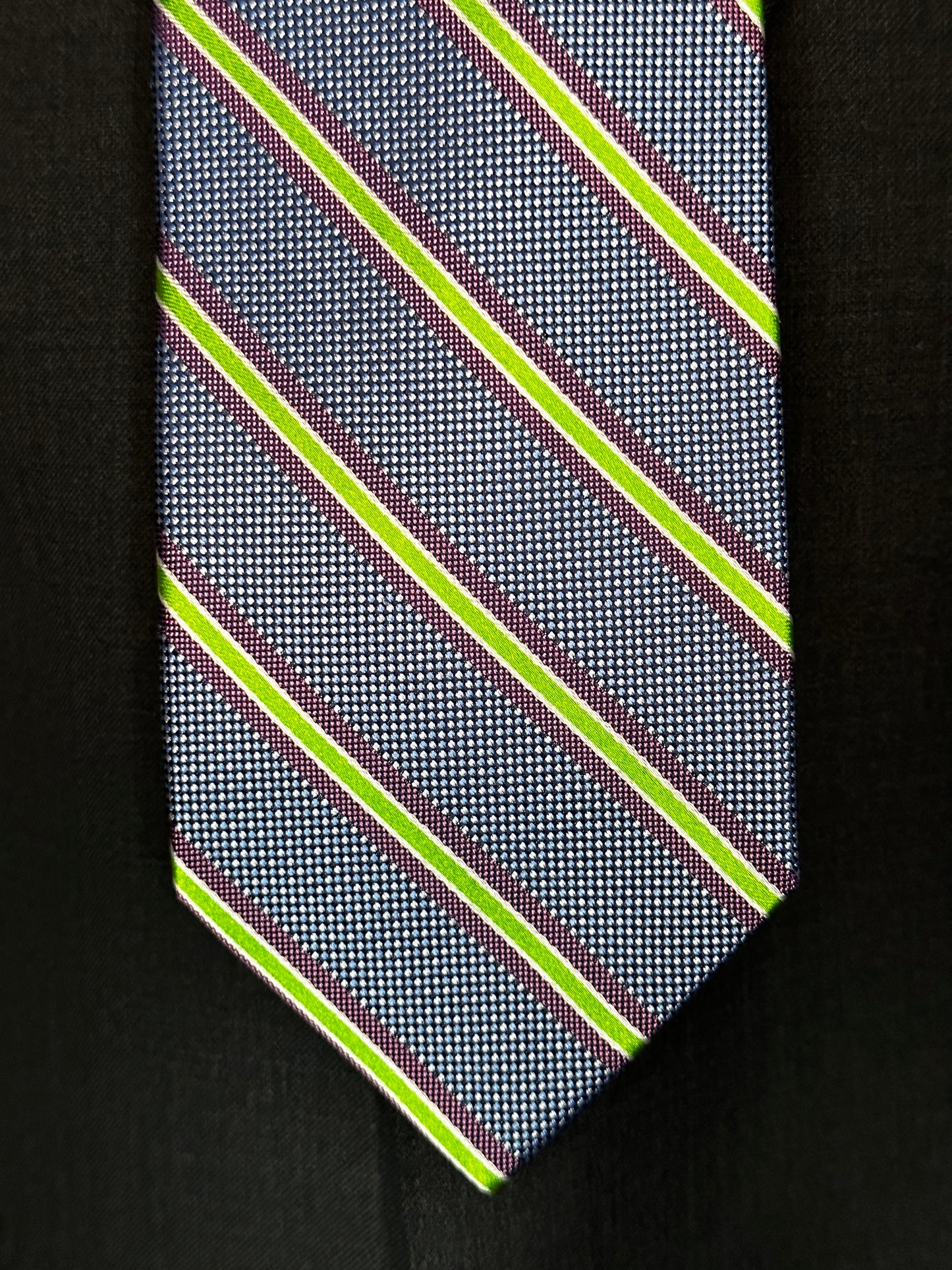 A general all around great tie to wear with any suit, shirt for any occasion. With two different types of silk in the same necktie, the stripe being satin and the broad section being woven, this tie makes an all day knot that does not have to be readjusted. With colorations of kelly green and purple stripes, you cannot make a mistake creating a look with this tie pairing with any suit in your closet.