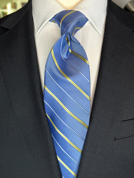 This pale blue woven silk necktie has two different types of silk. The yellow stripes are satin silk with the broad stripes in 100% woven silk. Easily used on a sky blue or white shirt with a multiple array of different suit colors, this tie fits well for daytime and evening time use.