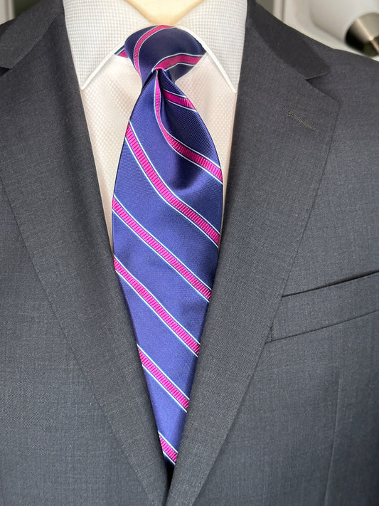 100% silk necktie in classic navy blue background with a stunning woven silk pink stripe. This tie is fantastic with the classic suits of navy, charcoal grey and pinstripes. Excellent with a crisp white french cuff shirt.