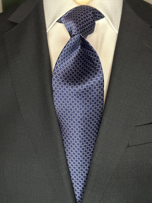 This satin finish 100% silk necktie has a very interesting all over geometric pattern of interlocking white links almost chain link in style. The silk is very smooth to the touch and has a natural luster that shines in certain light. This is a serious tie. Great for those business meetings, court dates, daytime or evening events, and all around more formal attire. This is best paired with a fancy white or tone on tone white dress shirt.