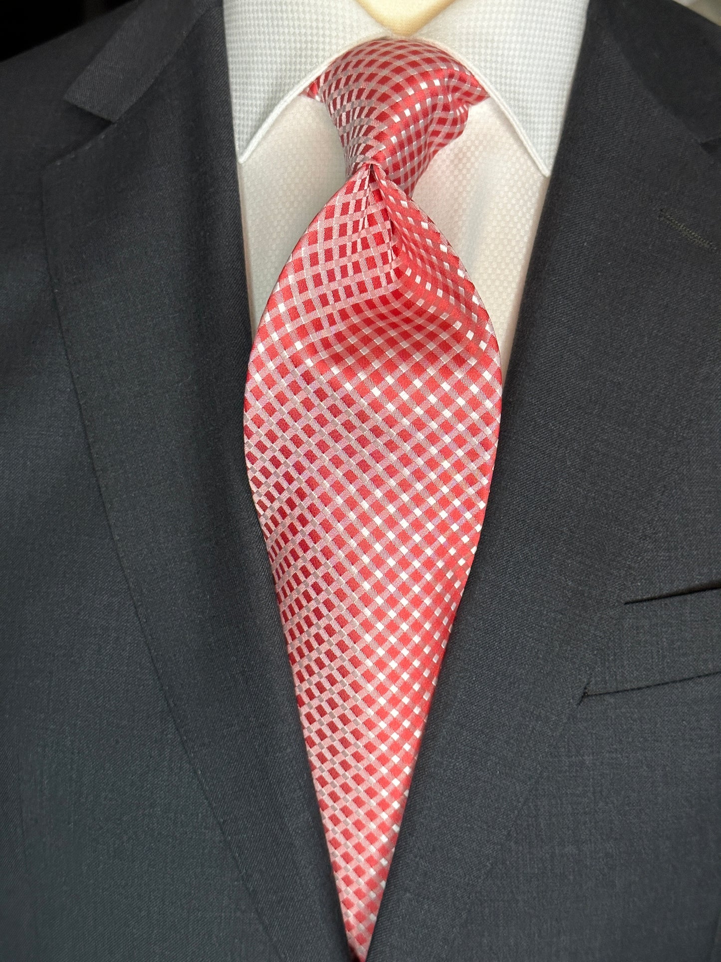 Add a touch of elegance to your wardrobe with this luxurious red silk tie. The diamond-shaped geometric lattice pattern in pale grey is meticulously woven into the fabric, creating a subtle yet sophisticated texture. The all-over pattern is composed of small squares that interlock to create a mesmerizing visual effect. This tie is crafted from the finest silk, ensuring that it will be a timeless addition to any collection.