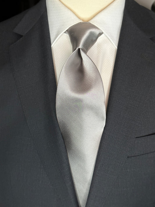 Solid ties are beautifully paired with the more busy of patters of bold stripes and heavy plaids. However, there is something so understated and elegant about a solid tie with a solid suit. Whether that be navy, charcoal or black a silver tie fits well with a white shirt and even a navy blazer with jeans. Silver necktie can also be used with formal wear.