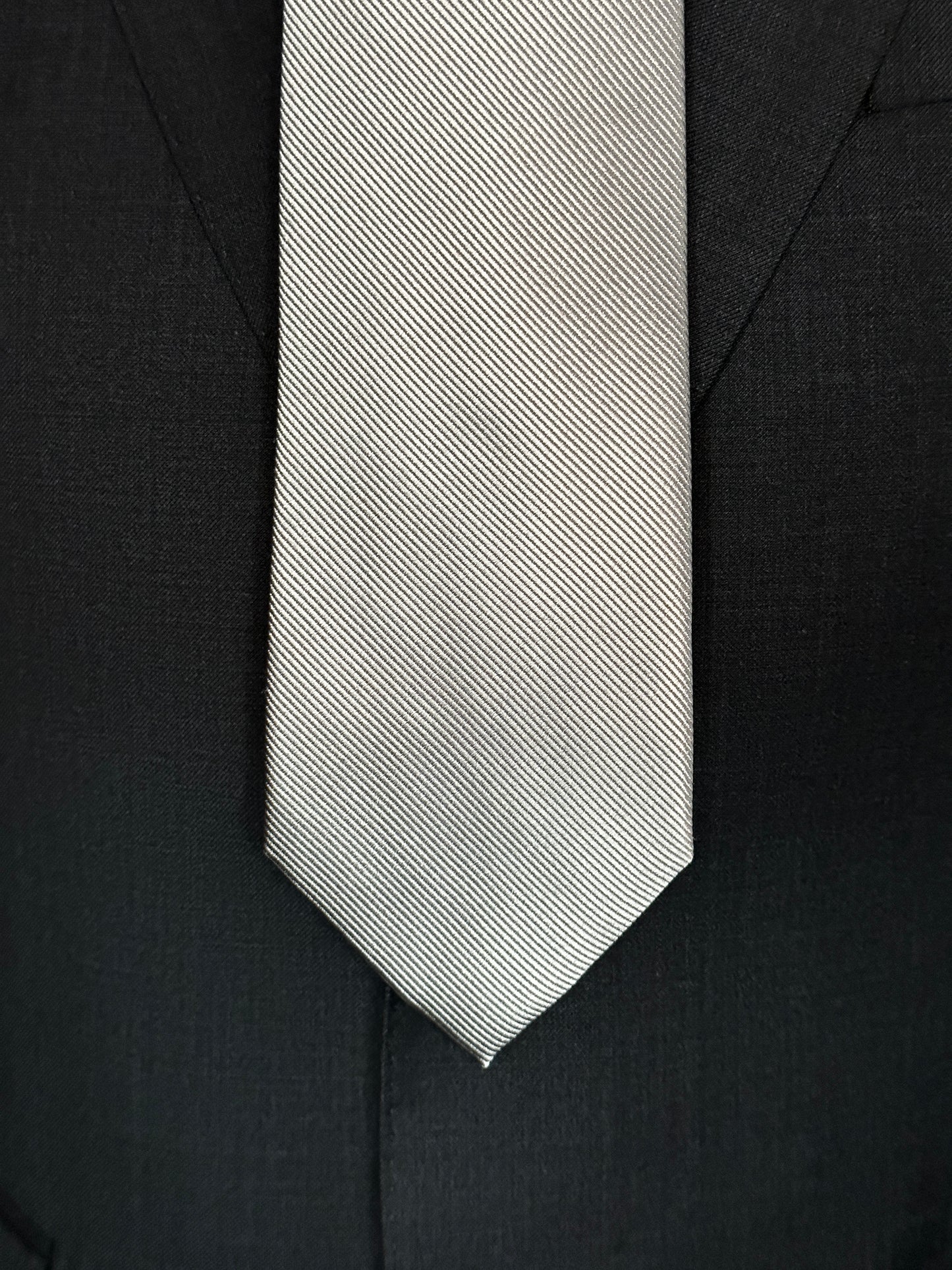 Solid ties are beautifully paired with the more busy of patters of bold stripes and heavy plaids. However, there is something so understated and elegant about a solid tie with a solid suit. Whether that be navy, charcoal or black a silver tie fits well with a white shirt and even a navy blazer with jeans. Silver necktie can also be used with formal wear.