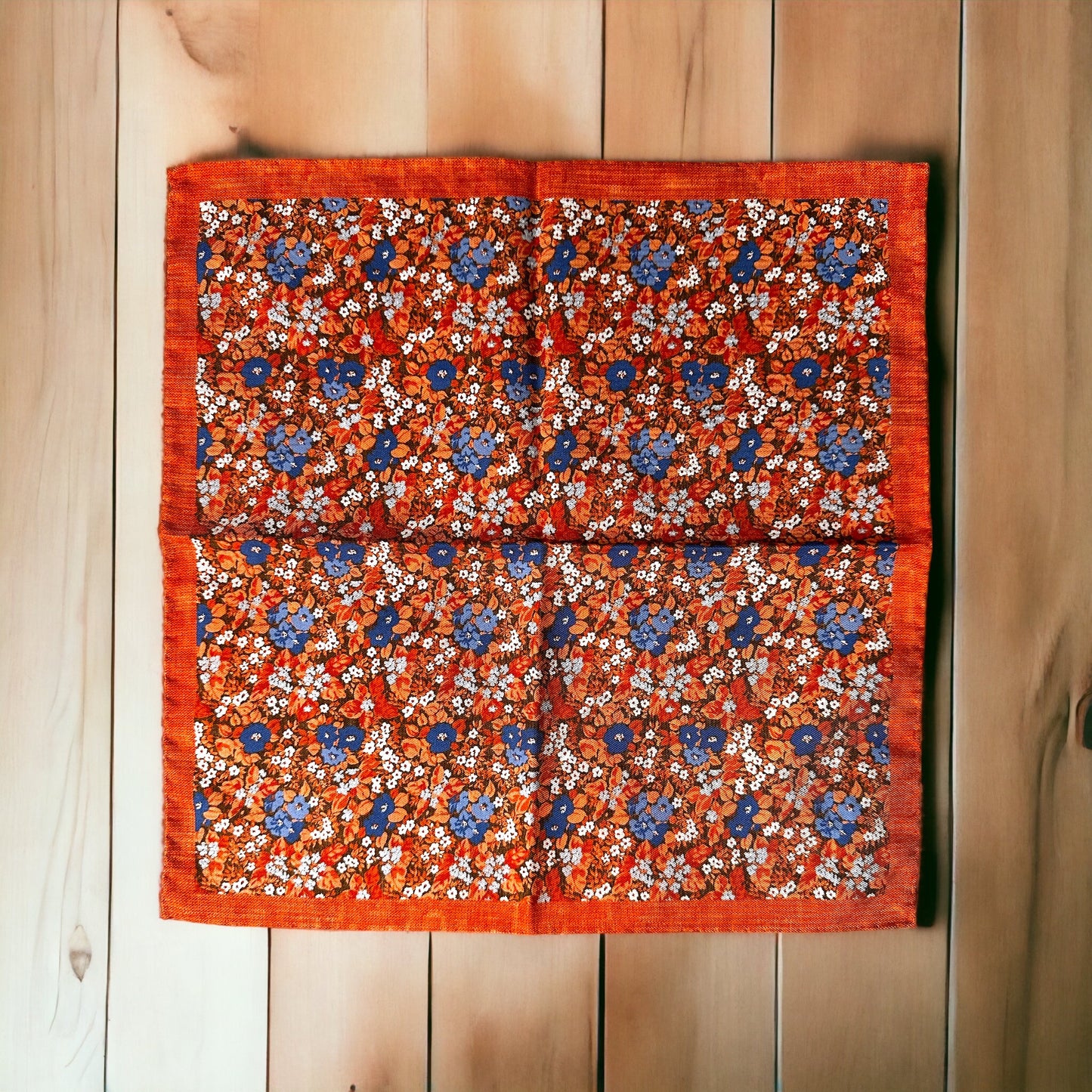 Hand rolled edges on this silk pocket square create gorgeous points that keep their position when using the breast pocket on a jacket. The orange silk with light blue mini floral design and white min daisies is a stunning classic all around geometric design. On the reverse is a different fun pattern of different colorful and shaped stripes. A fun and playful pocket square for every occasion.