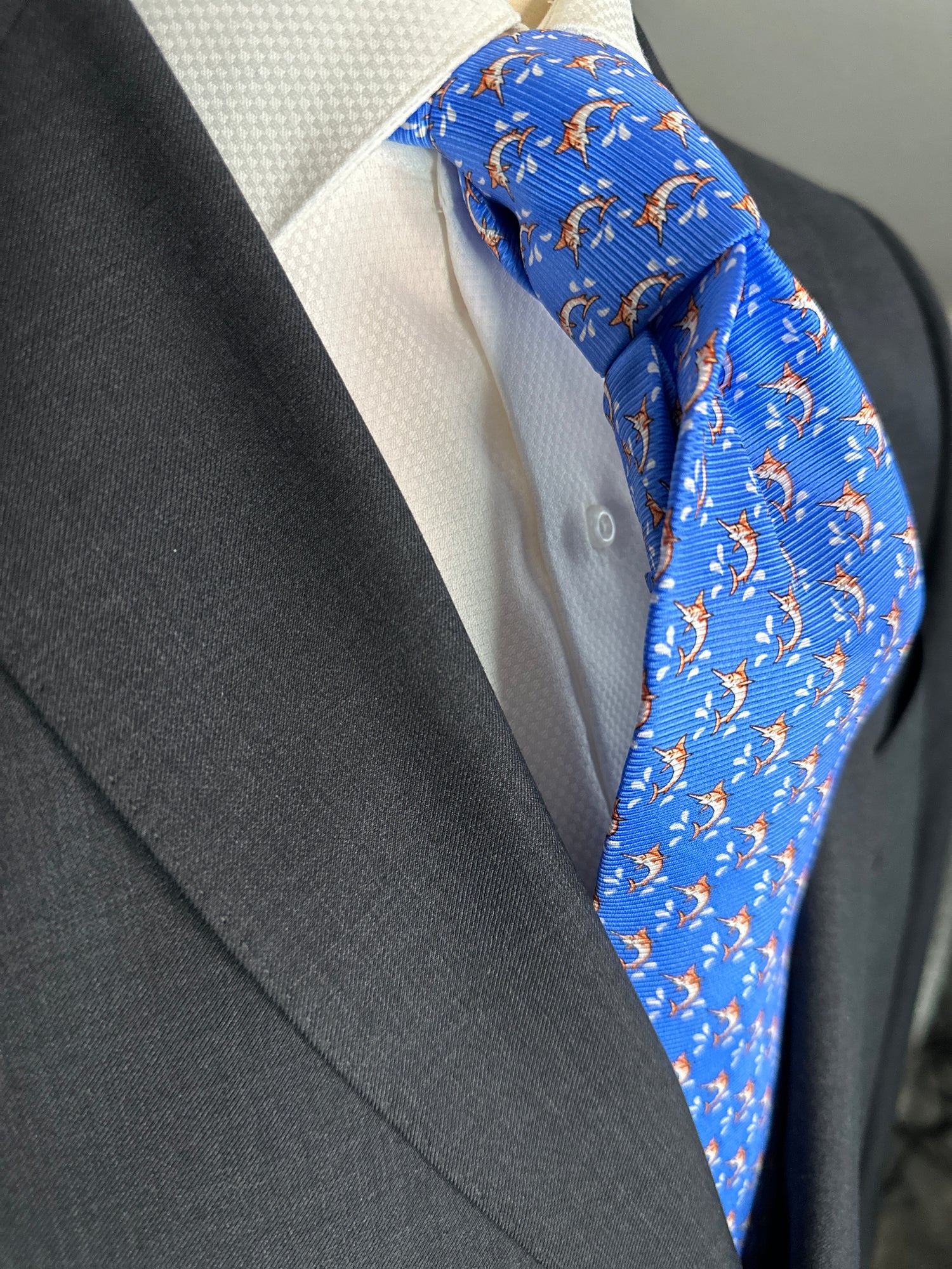 This beautiful 100% silk twill necktie features the swordfish motif with small splashes of water. Being a geometric type pattern, this tie is most interesting because people tend to look twice to realize that the pattern is made up of orange/tan swordfish. Hermes style..