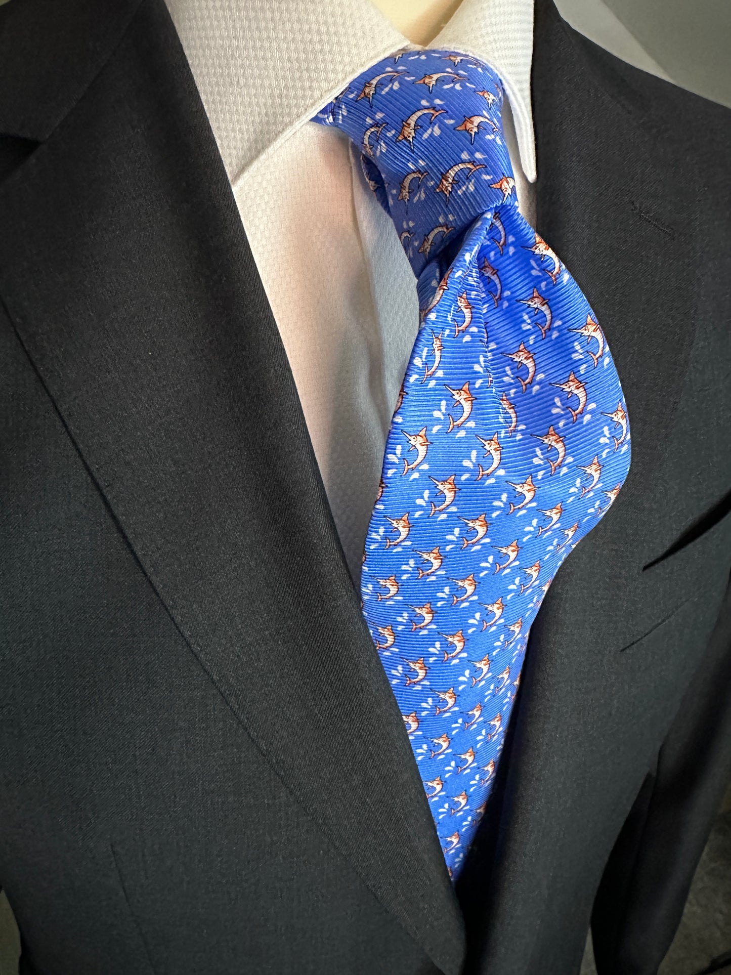 This beautiful 100% silk twill necktie features the swordfish motif with small splashes of water. Being a geometric type pattern, this tie is most interesting because people tend to look twice to realize that the pattern is made up of orange/tan swordfish. Hermes style..