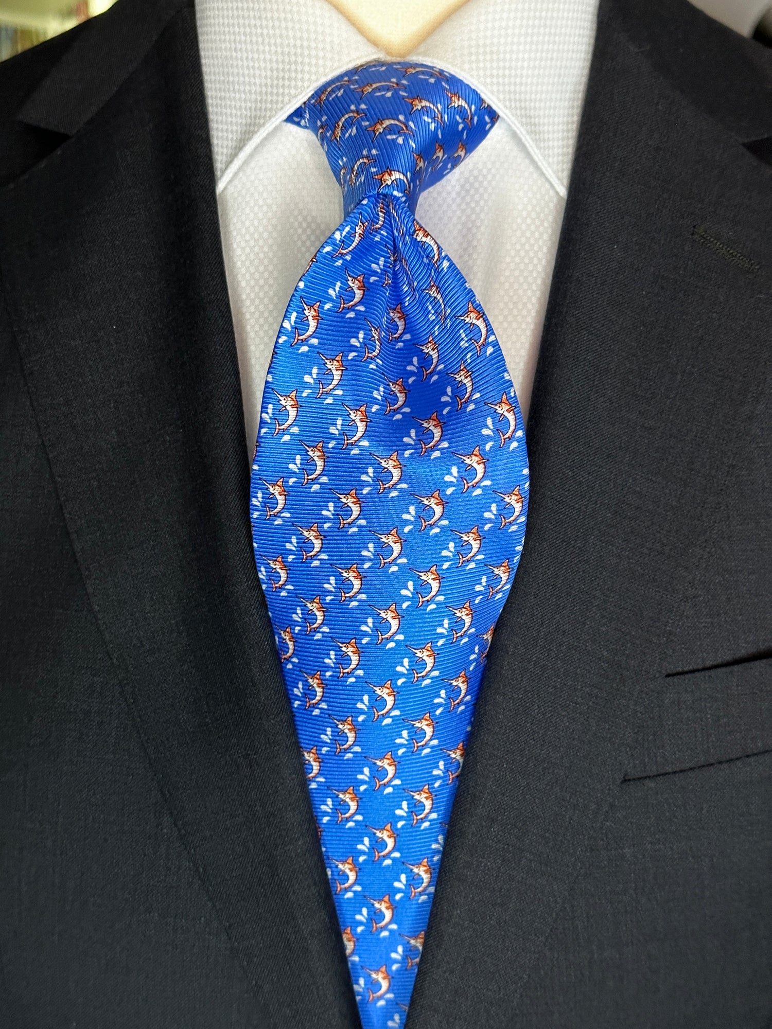 This beautiful 100% silk twill necktie features the swordfish motif with small splashes of water. Being a geometric type pattern, this tie is most interesting because people tend to look twice to realize that the pattern is made up of orange/tan swordfish. Hermes style.