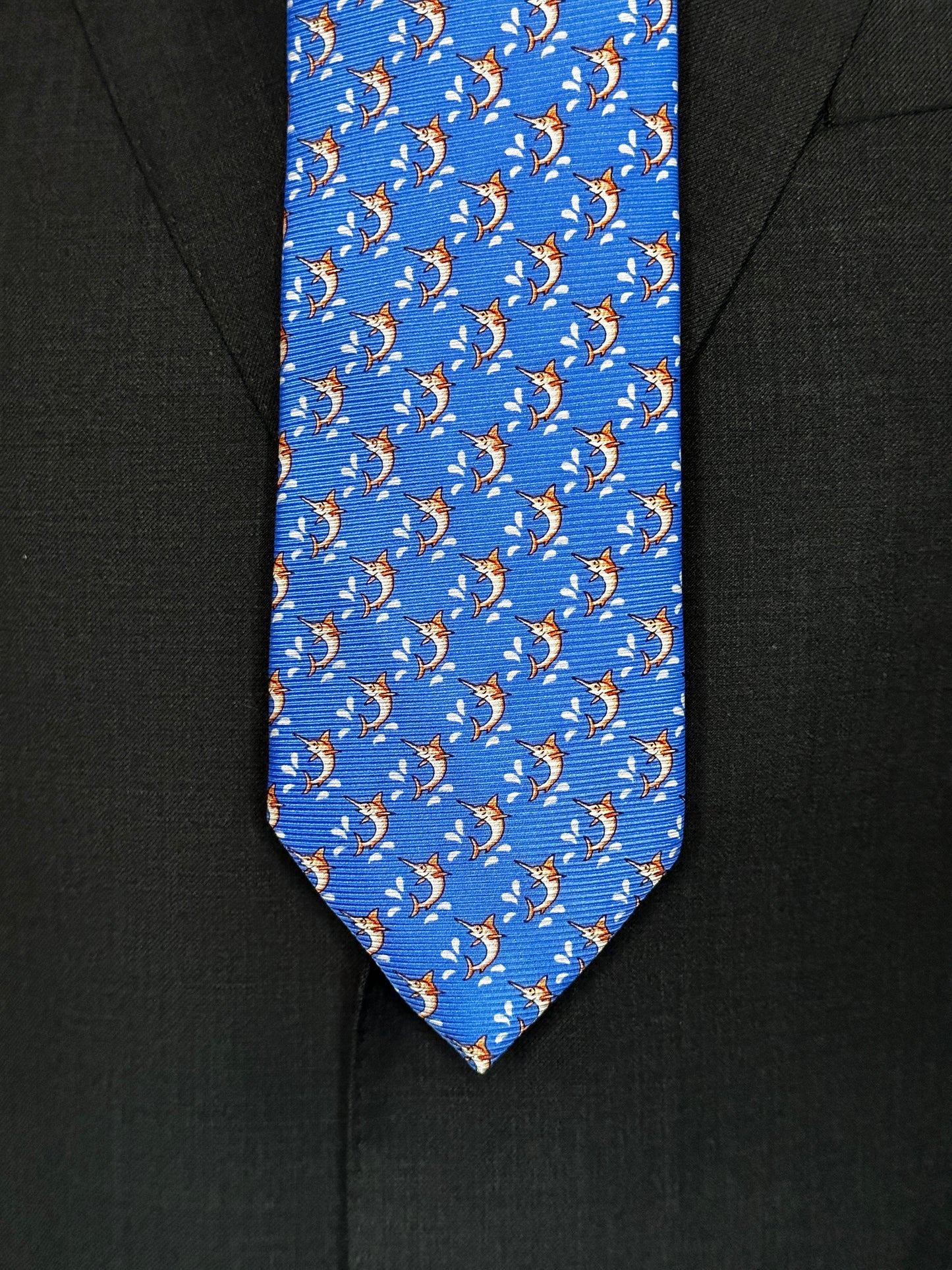 This beautiful 100% silk twill necktie features the swordfish motif with small splashes of water. Being a geometric type pattern, this tie is most interesting because people tend to look twice to realize that the pattern is made up of orange/tan swordfish. Hermes style..