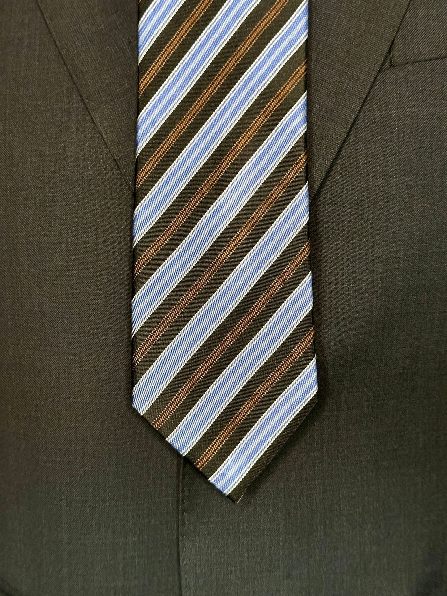 A wonderful 100% silk woven tie in clean stripes. Here we have a complimentary mixture of colors from brown and black with baby blue and white. This tie is a great business tie and would look great paired with many suit variations from black, navy, charcoal and pinstripes as well. Suits with windowpanes always do well with striped neckwear.