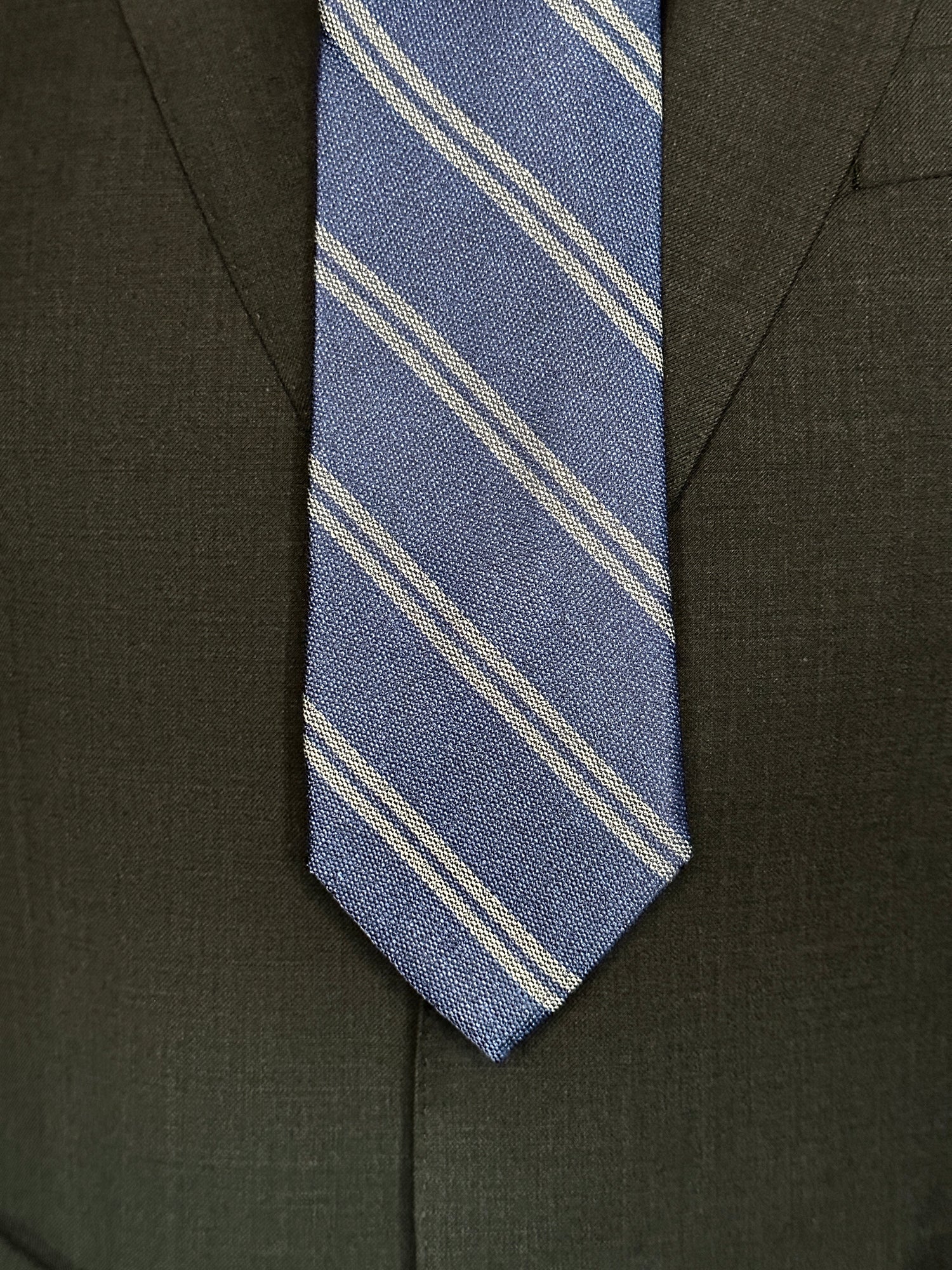 The textured woven silk of this blue denim tie is perfect for all seasons. The texture goes well with wool flannels, plaids and interesting mini checks. Made from 100% silk, the denim blue necktie combines well with pure white for that contrast or a pale grey to bring out the double charcoal stripe in the tie.