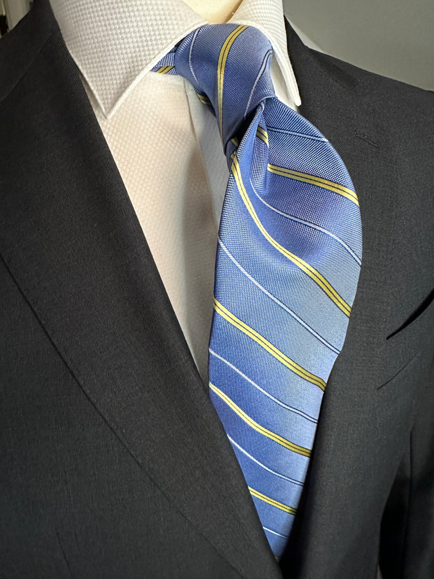 This pale blue woven silk necktie has two different types of silk. The yellow stripes are satin silk with the broad stripes in 100% woven silk. Easily used on a sky blue or white shirt with a multiple array of different suit colors, this tie fits well for daytime and evening time use.