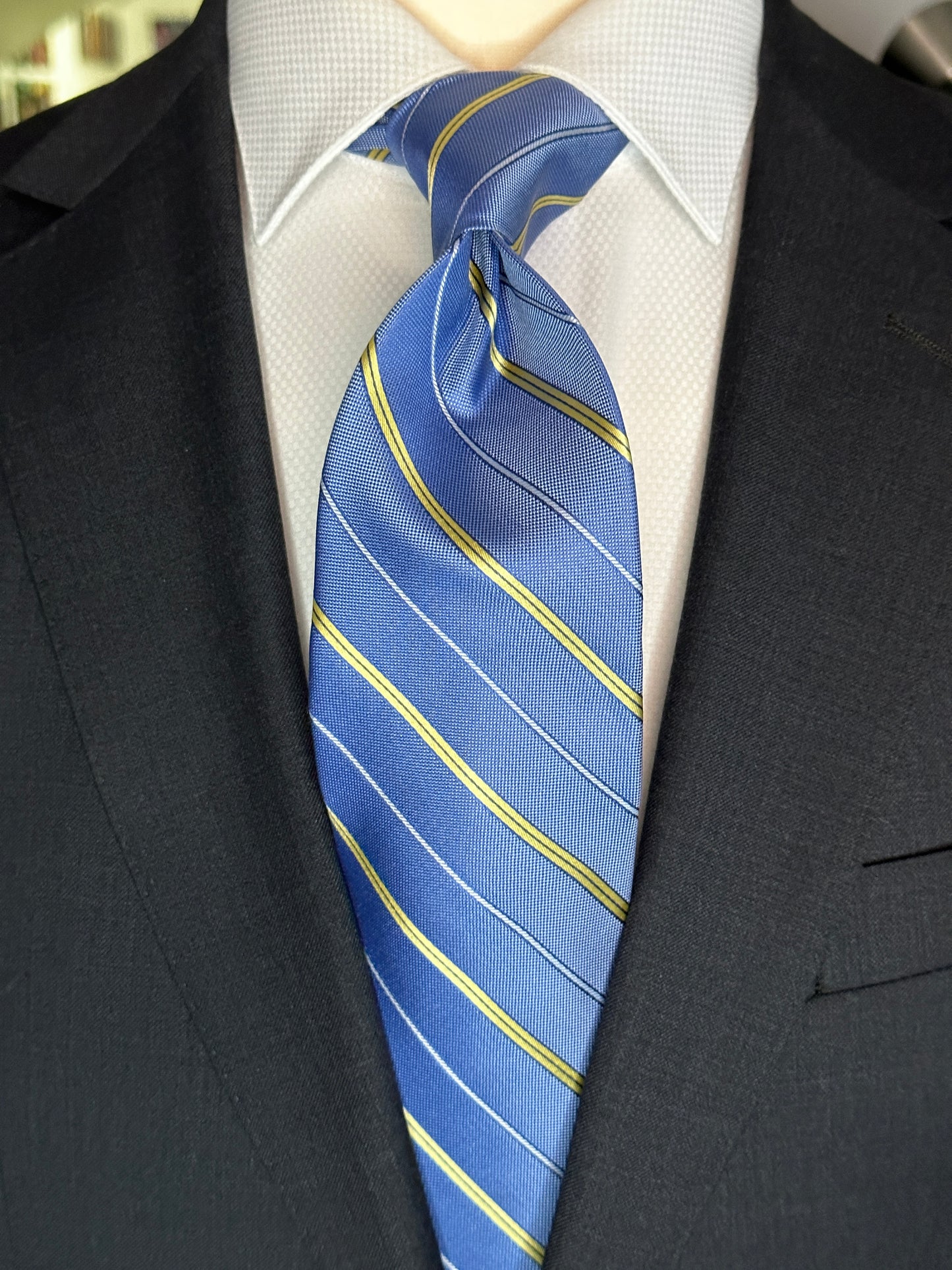 This pale blue woven silk necktie has two different types of silk. The yellow stripes are satin silk with the broad stripes in 100% woven silk. Easily used on a sky blue or white shirt with a multiple array of different suit colors, this tie fits well for daytime and evening time use.