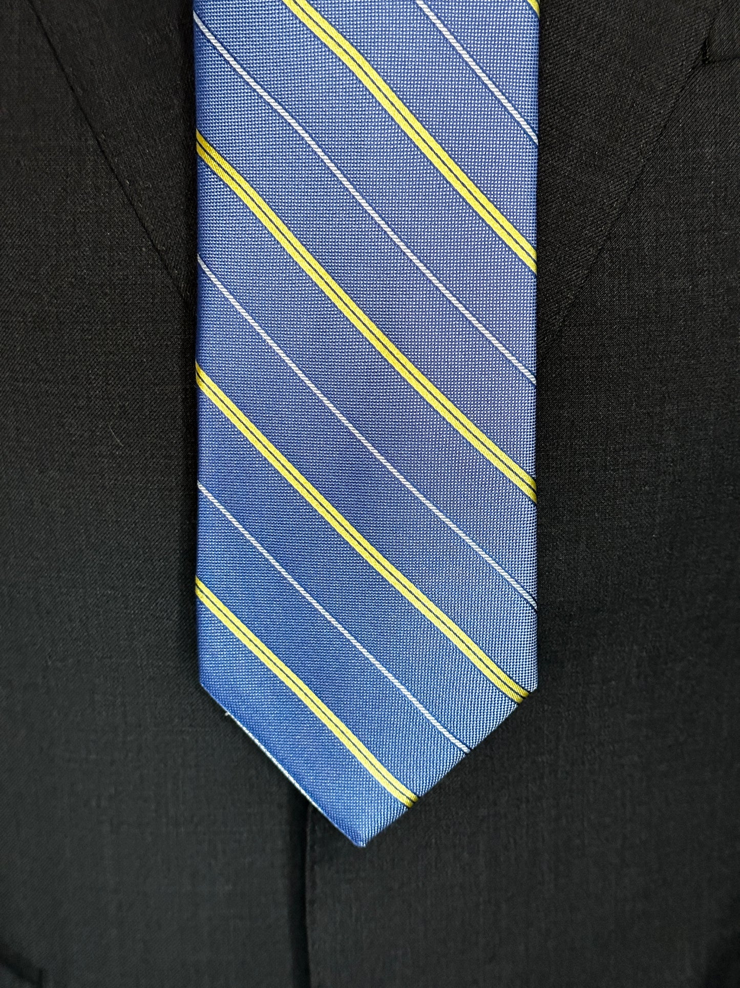 This pale blue woven silk necktie has two different types of silk. The yellow stripes are satin silk with the broad stripes in 100% woven silk. Easily used on a sky blue or white shirt with a multiple array of different suit colors, this tie fits well for daytime and evening time use.