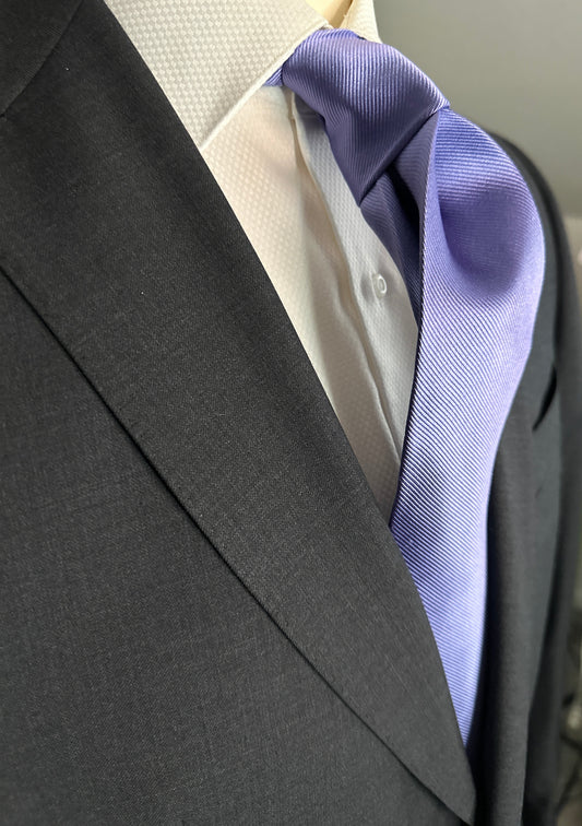Solid ties are beautifully paired with the more busy of patters of bold stripes and heavy plaids. However, there is something so understated and elegant about a solid tie with a solid suit. Whether that be navy, charcoal or black a lavender tie fits well with a white shirt and even a navy blazer with jeans.