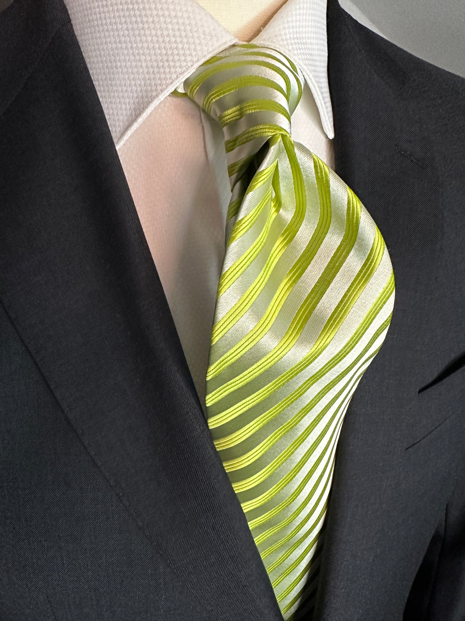 This stunning woven silk in lime green and pale green narrow striped tie. The woven silk fabric adds a luxurious texture and gives the tie an alluring sheen. The narrow stripes, delicately woven with precision, add depth and complexity to the design. The bright lime green color, complemented by the pale green stripes, is the perfect way to add a pop of color to your outfit. This tie is an absolute must-have for any fashion-forward individual who appreciates quality craftsmanship and timeless style.