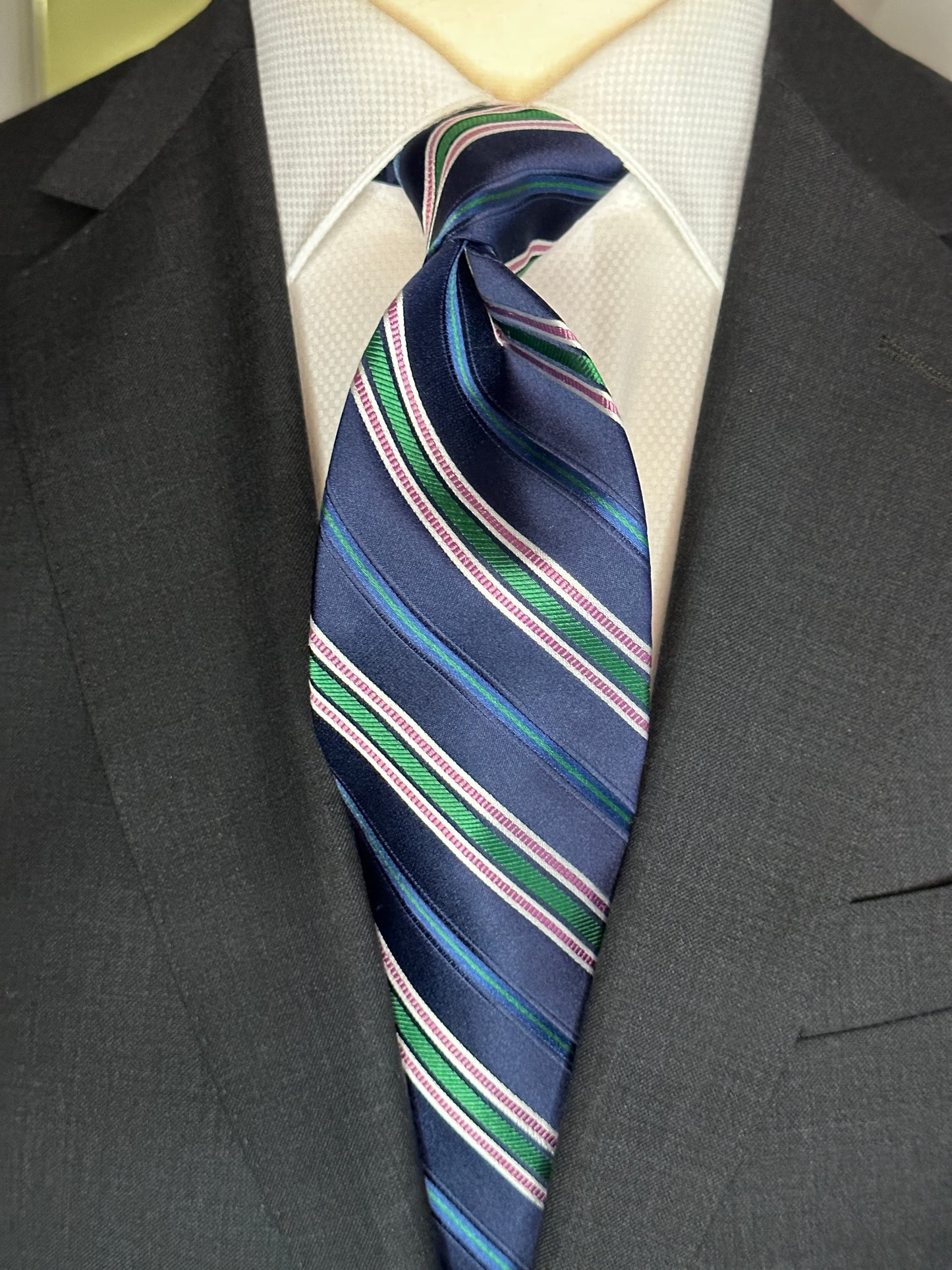 A multistripe tie has many functions. This 100% silk navy blue base tie has multiple types of stripes running through it. Light blue, rose, white ands green impact this toe in different widths. The multistripe tie allows for many types of colorations and patterns in shirts and suits. Probably the most versatile. 