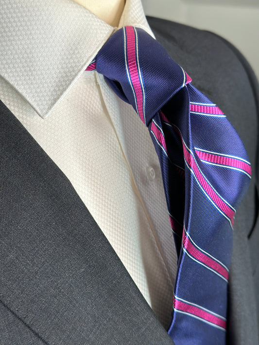 100% silk necktie in classic navy blue background with a stunning woven silk pink stripe. This tie is fantastic with the classic suits of navy, charcoal grey and pinstripes. Excellent with a crisp white french cuff shirt. 