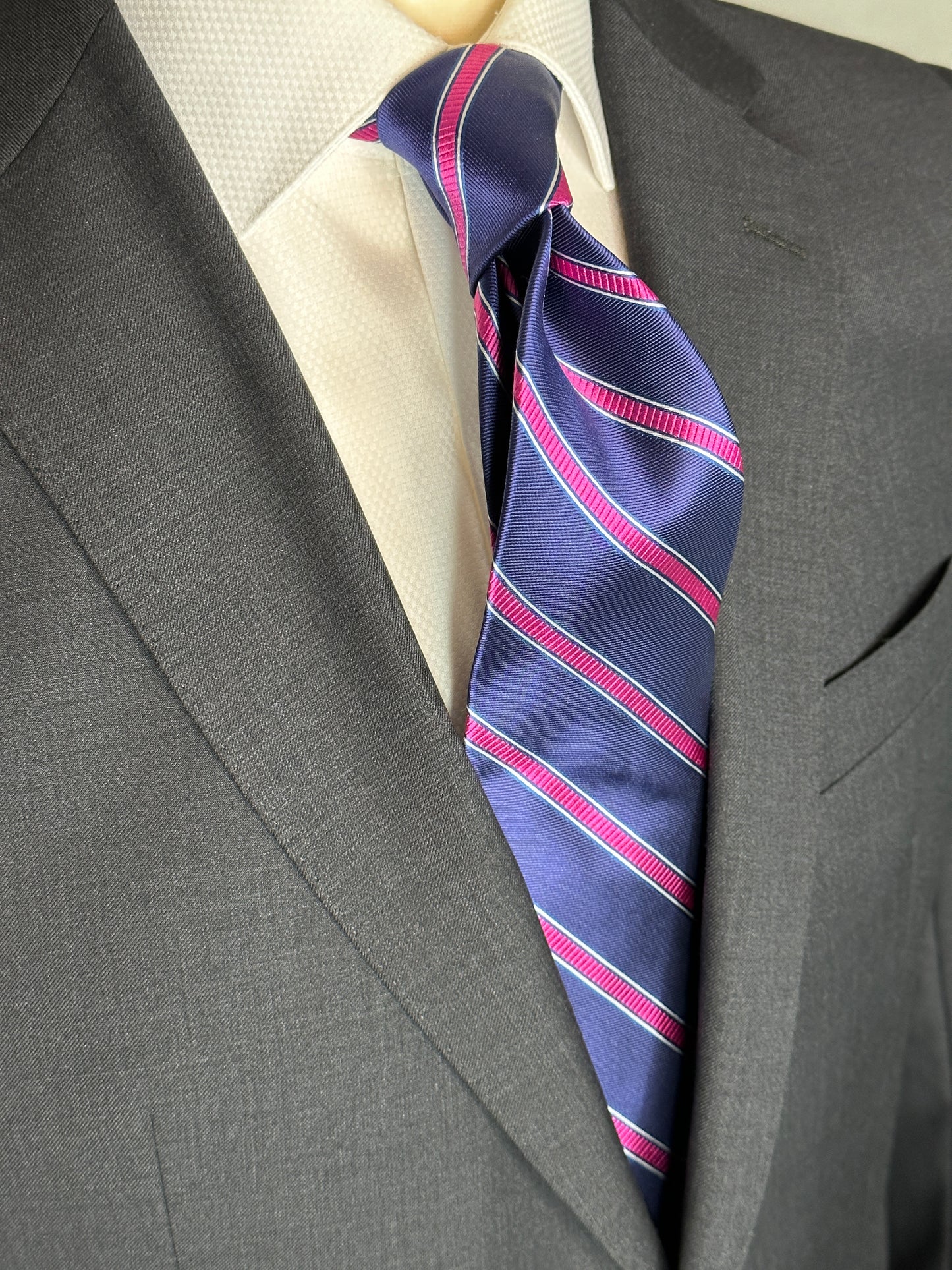 100% silk necktie in classic navy blue background with a stunning woven silk pink stripe. This tie is fantastic with the classic suits of navy, charcoal grey and pinstripes. Excellent with a crisp white french cuff shirt. 