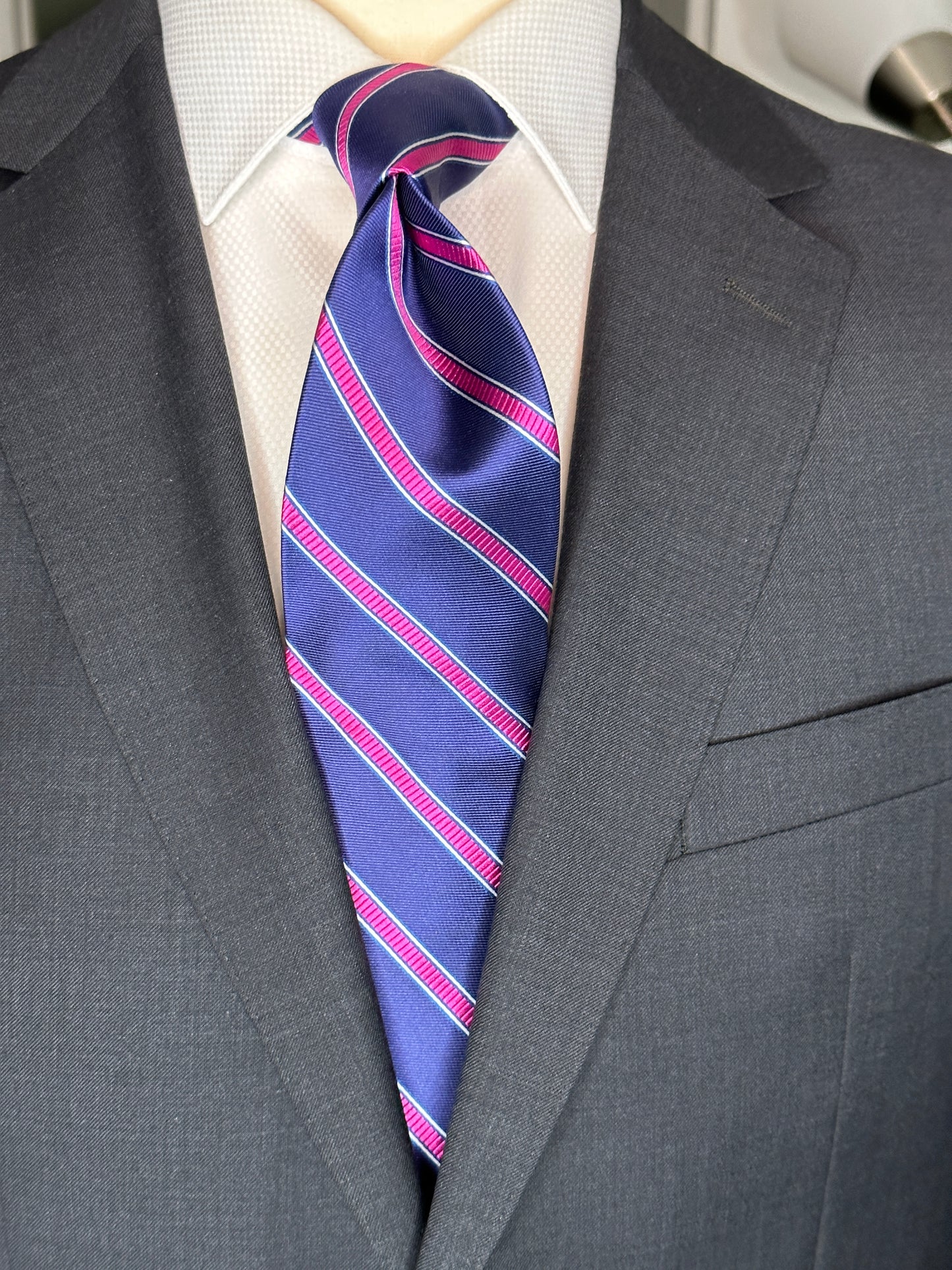 100% silk necktie in classic navy blue background with a stunning woven silk pink stripe. This tie is fantastic with the classic suits of navy, charcoal grey and pinstripes. Excellent with a crisp white french cuff shirt. 