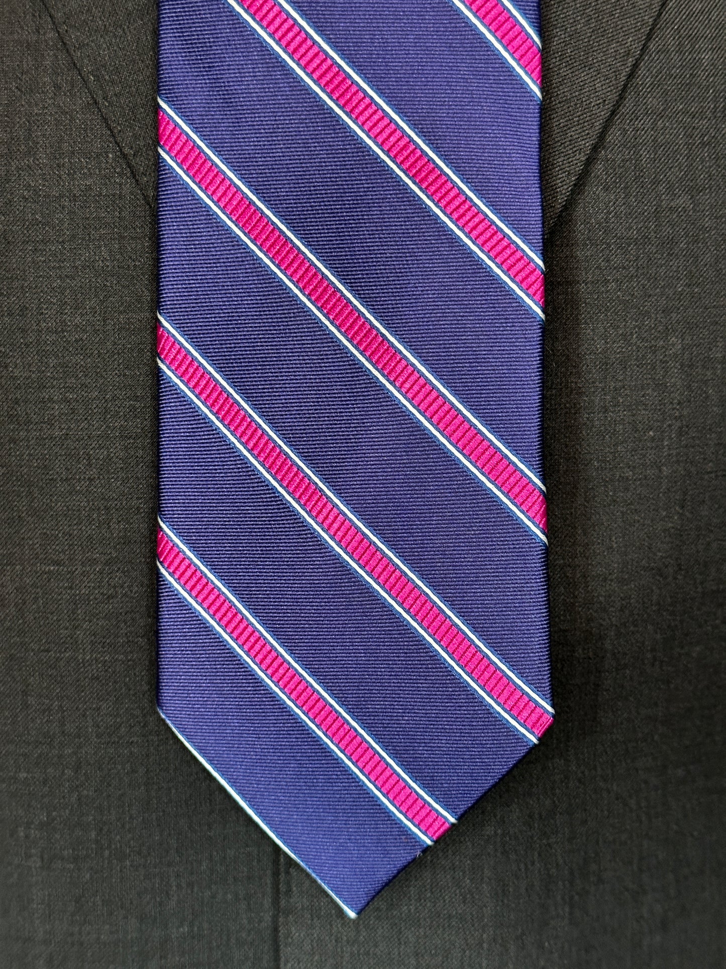 100% silk necktie in classic navy blue background with a stunning woven silk pink stripe. This tie is fantastic with the classic suits of navy, charcoal grey and pinstripes. Excellent with a crisp white french cuff shirt. 