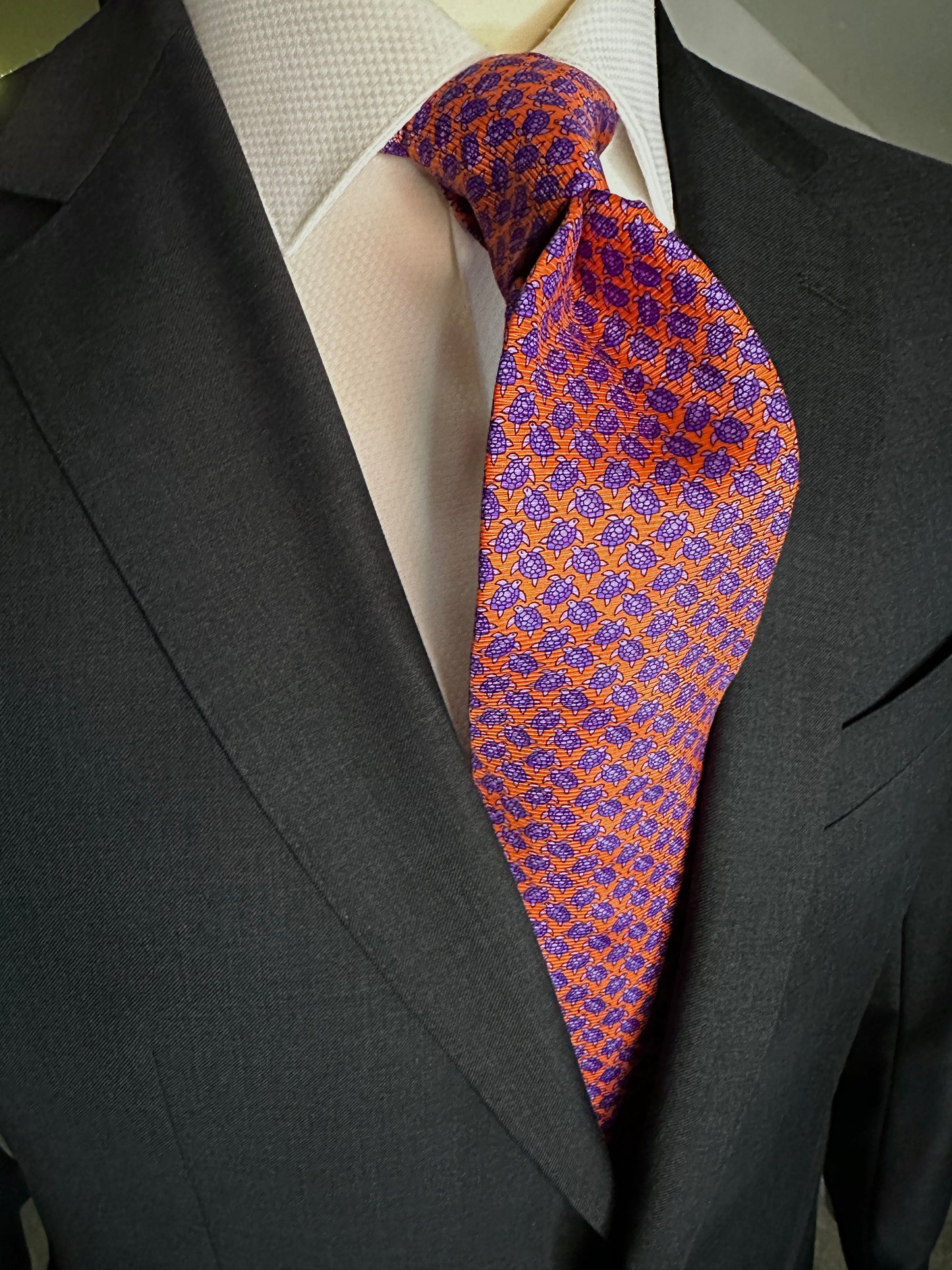 A tie with turtles, what could be better? You don't see turtles? This beautiful geometric pattern is made of closely bunched turtles in purple against an orange background. What is so great about this tie is that from afar this necktie is a neat pattern, but as you get closer it can be seen there are small turtles together. Hermes style. 