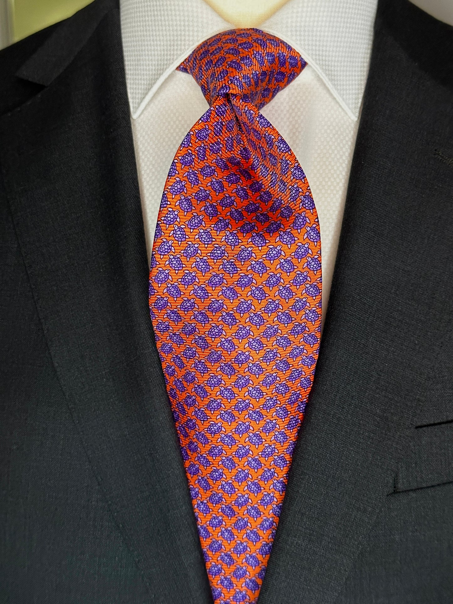 A tie with turtles, what could be better? You don't see turtles? This beautiful geometric pattern is made of closely bunched turtles in purple against an orange background. What is so great about this tie is that from afar this necktie is a neat pattern, but as you get closer it can be seen there are small turtles together. Hermes style. 