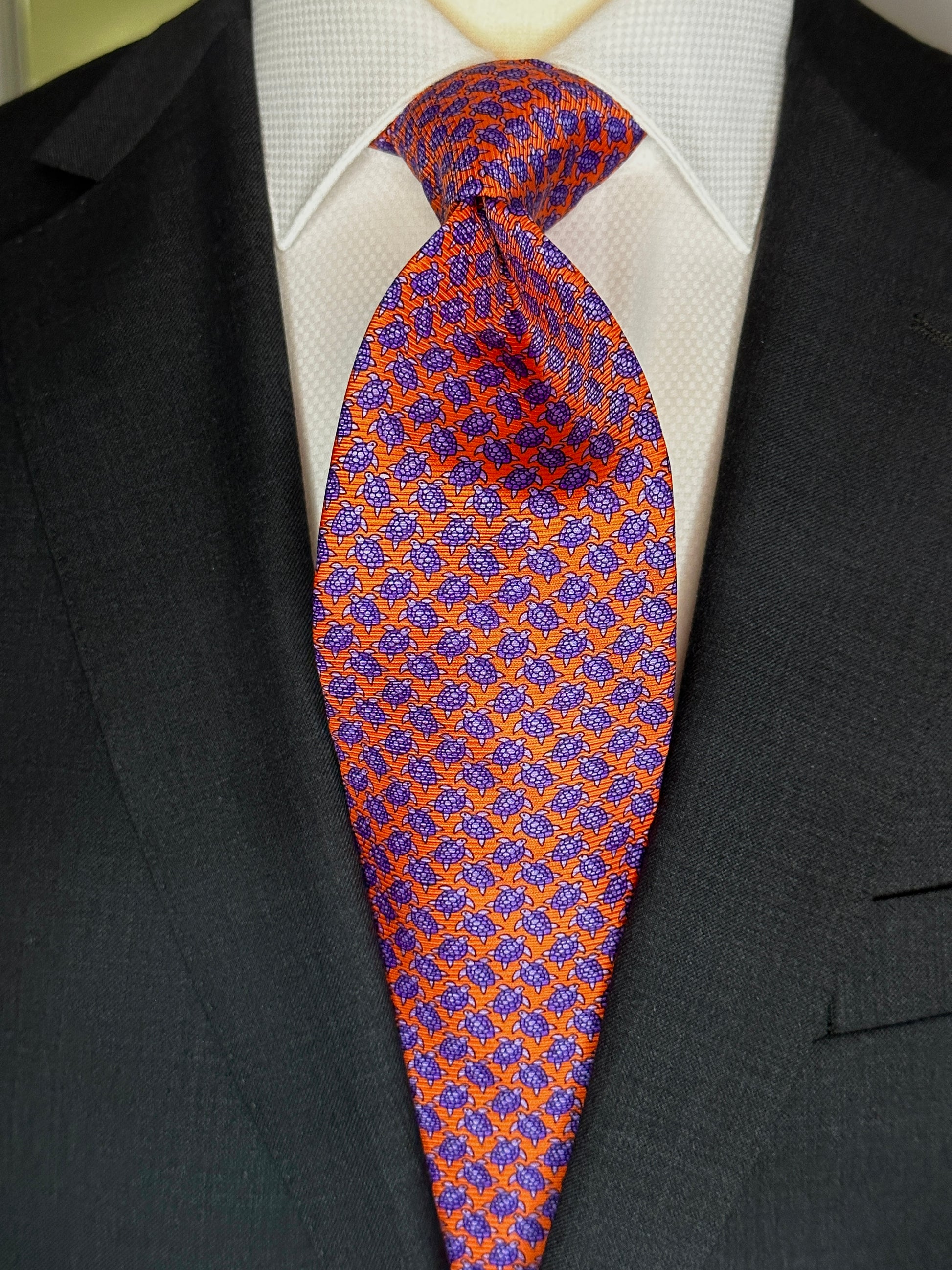A tie with turtles, what could be better? You don't see turtles? This beautiful geometric pattern is made of closely bunched turtles in purple against an orange background. What is so great about this tie is that from afar this necktie is a neat pattern, but as you get closer it can be seen there are small turtles together. Hermes style. 