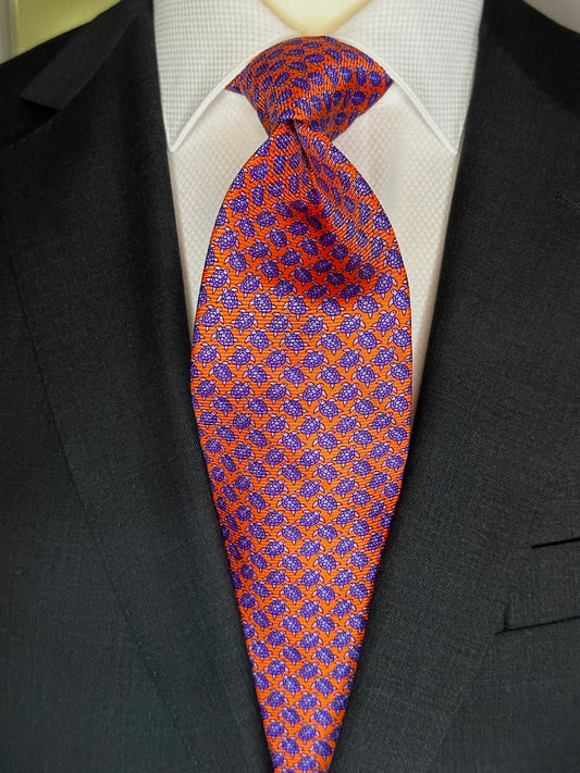 A tie with turtles, what could be better? You don't see turtles? This beautiful geometric pattern is made of closely bunched turtles in purple against an orange background. What is so great about this tie is that from afar this necktie is a neat pattern, but as you get closer it can be seen there are small turtles together. Hermes style. 