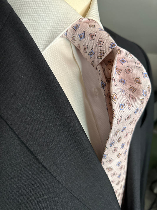 A 100% silk tie in pastel pink that has the characteristics and feel of linen. For those light weight summer outfits and thin cotton summer dress shirts, including Swiss voile, you need a tie that carries the same type of personality. The weave of this silk looks like the weave of pure linen, but has the smooth feel of silk. 