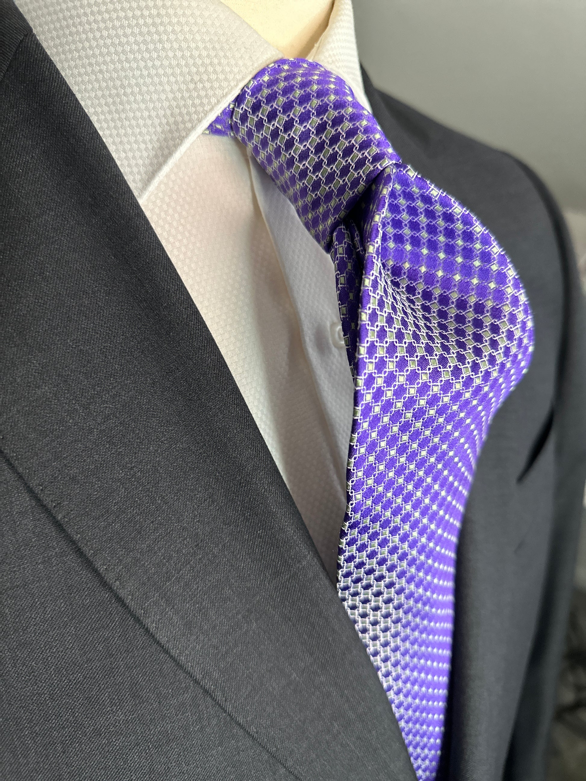 This 100% silk necktie is made from the finest Italian woven silk. The pattern is a small neat geometric making for a cool, crisp look. Inside each small checkered square is a small pale green square. This is a very sophisticated tie for business, dinners or even a wedding.