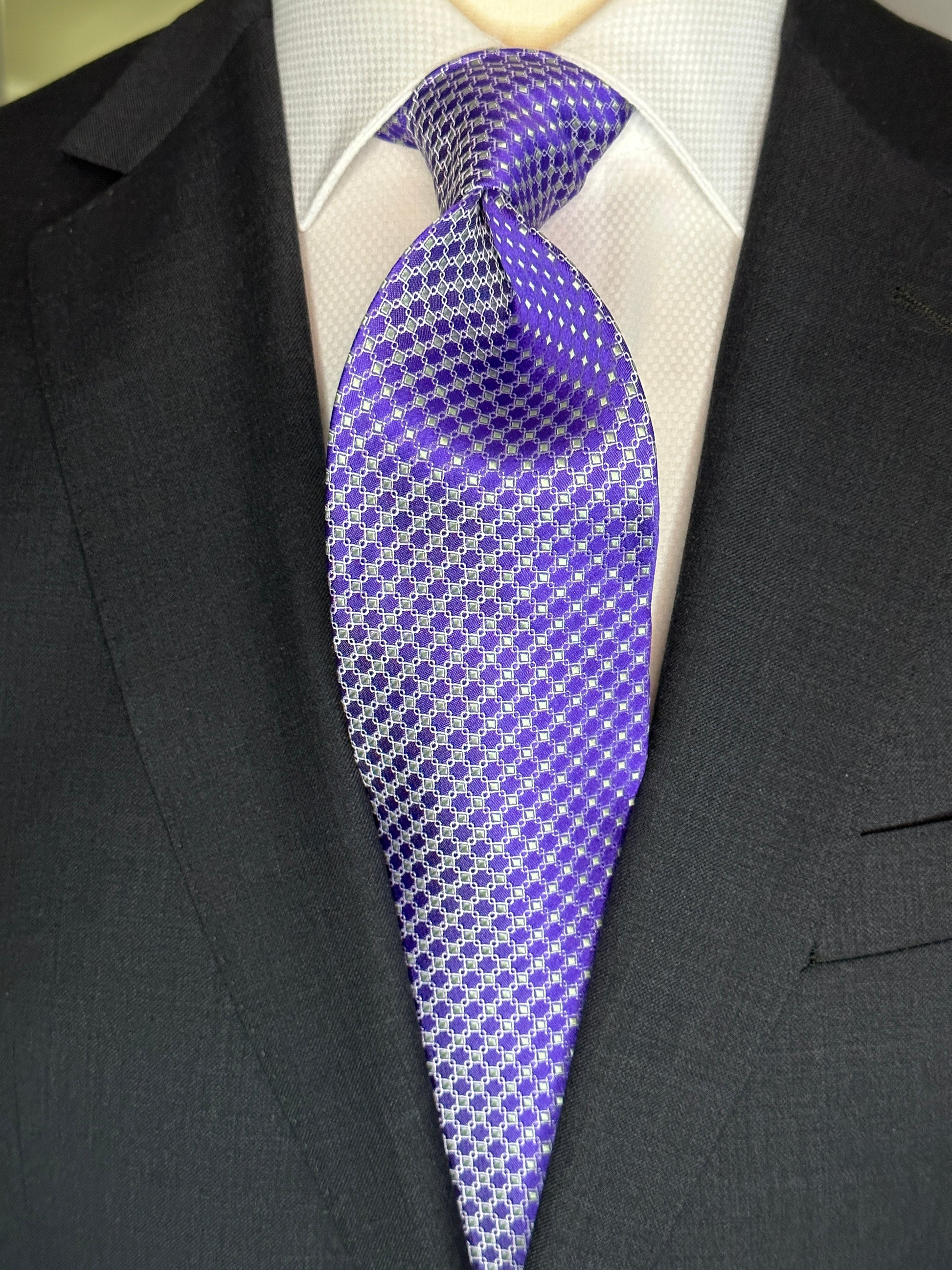 This 100% silk necktie is made from the finest Italian woven silk. The pattern is a small neat geometric making for a cool, crisp look. Inside each small checkered square is a small pale green square. This is a very sophisticated tie for business, dinners or even a wedding.