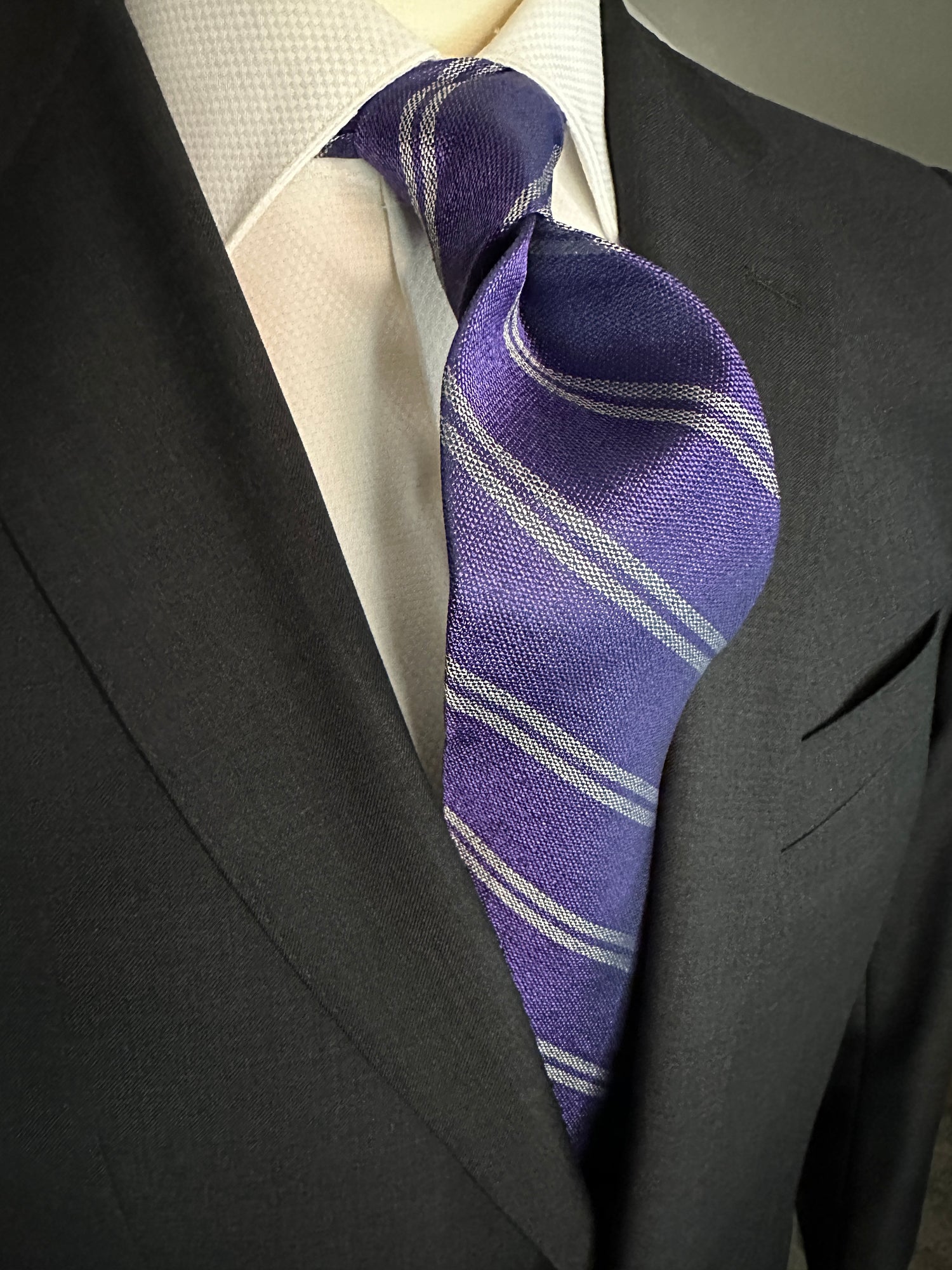 The textured woven silk of this purple silk tie is perfect for all seasons. The texture goes well with wool flannels, plaids and interesting mini checks. Made from 100% silk, the purple texture necktie combines well with pure white for that contrast or a pale grey to bring out the double charcoal stripe in the tie. 