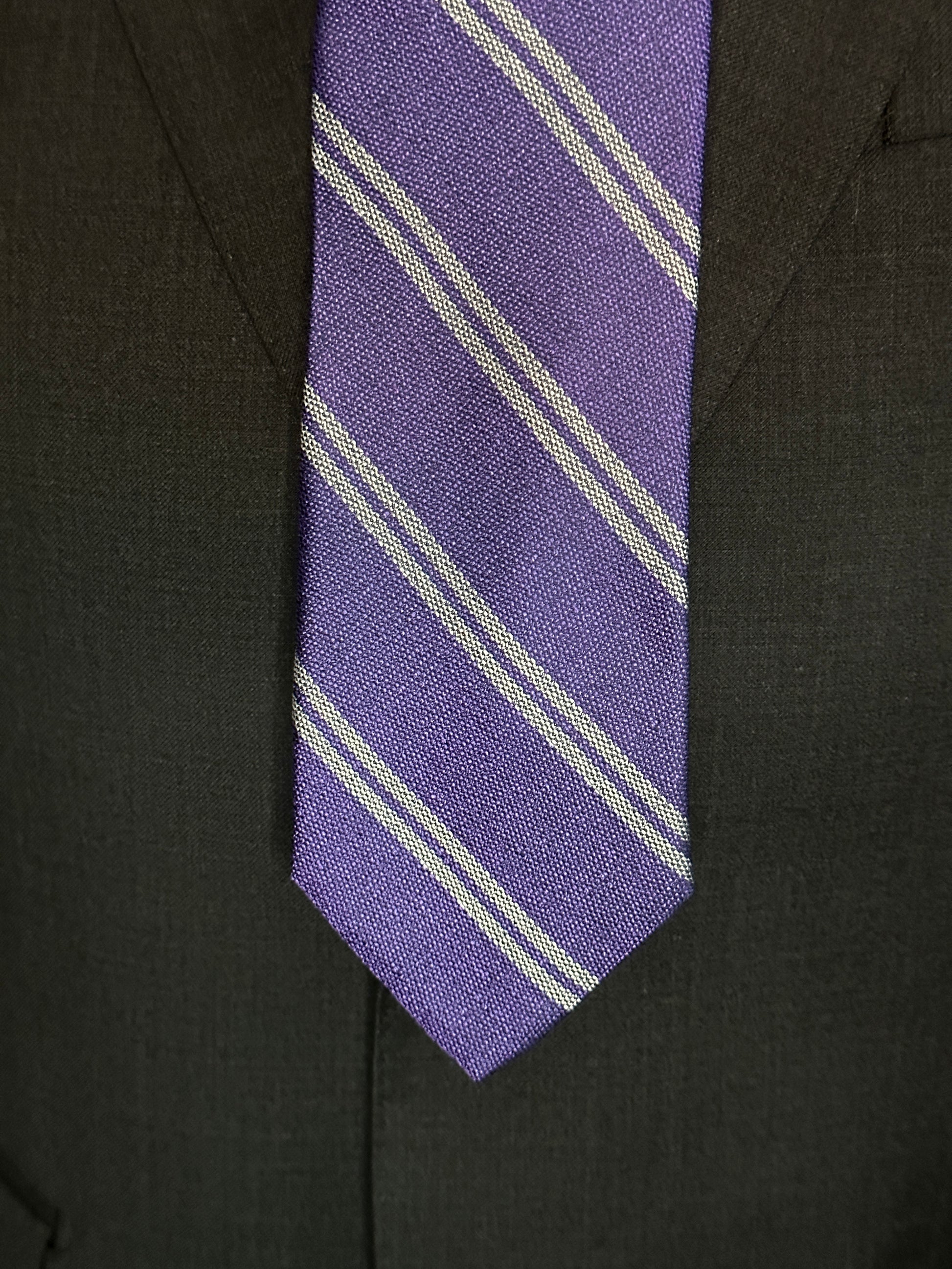 The textured woven silk of this purple silk tie is perfect for all seasons. The texture goes well with wool flannels, plaids and interesting mini checks. Made from 100% silk, the purple texture necktie combines well with pure white for that contrast or a pale grey to bring out the double charcoal stripe in the tie. 