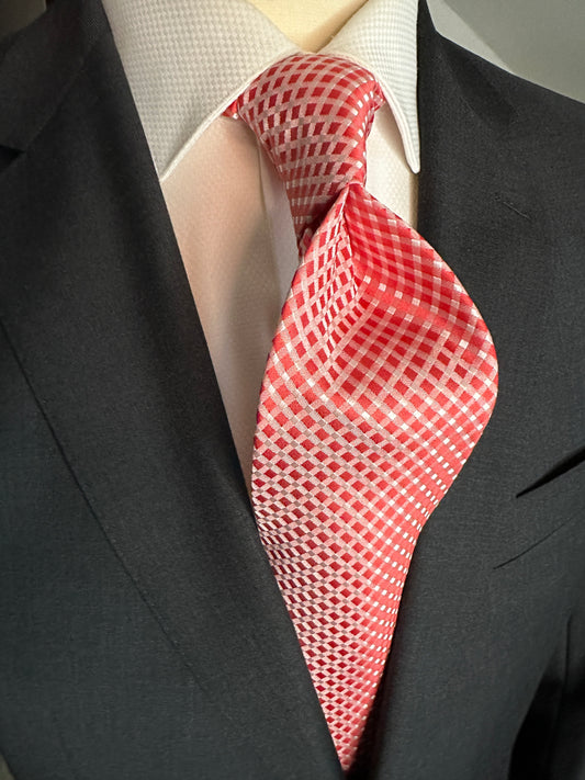 Add a touch of elegance to your wardrobe with this luxurious red silk tie. The diamond-shaped geometric lattice pattern in pale grey is meticulously woven into the fabric, creating a subtle yet sophisticated texture. The all-over pattern is composed of small squares that interlock to create a mesmerizing visual effect. This tie is crafted from the finest silk, ensuring that it will be a timeless addition to any collection.