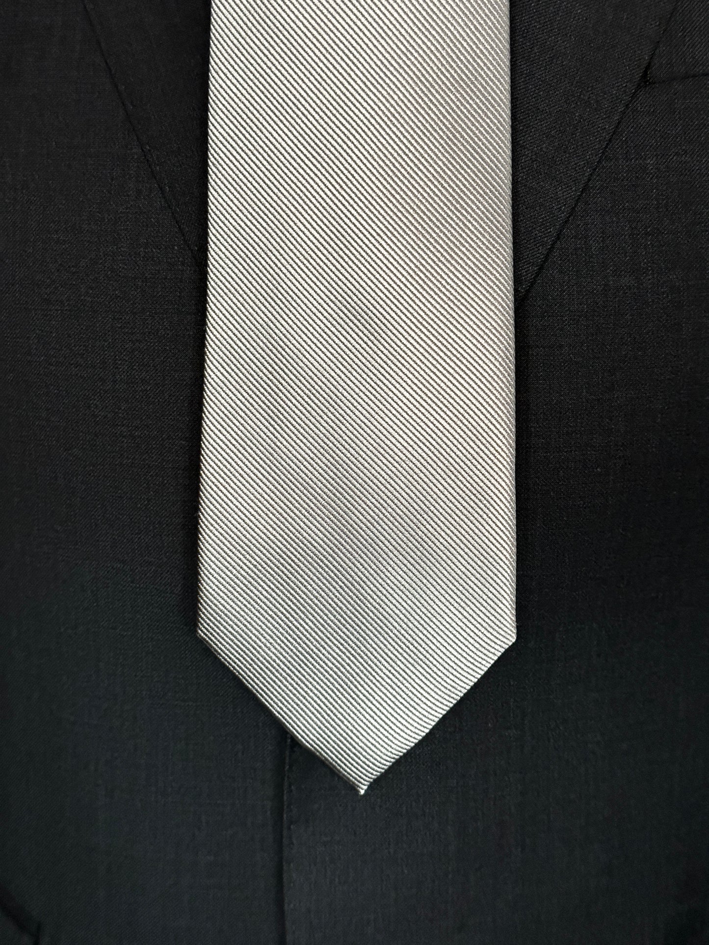 Solid ties are beautifully paired with the more busy of patters of bold stripes and heavy plaids. However, there is something so understated and elegant about a solid tie with a solid suit. Whether that be navy, charcoal or black a silver tie fits well with a white shirt and even a navy blazer with jeans. Silver necktie can also be used with formal wear. 