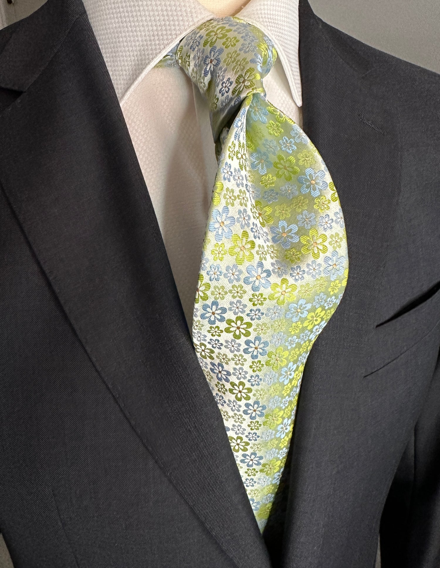 An amazing bright silk woven tie with summer mini florets. The characteristics of this tie coloration are very interesting in that it tends to take on the colors of what it is paired with. Take for instance the solid charcoal grey suit in the photos. This tie works very well with it. It would also go well with tan, black, navy, pinstripes, plaids and many others. There are always a few ties each season that tend to go with most colors and patterns and this is one of them.