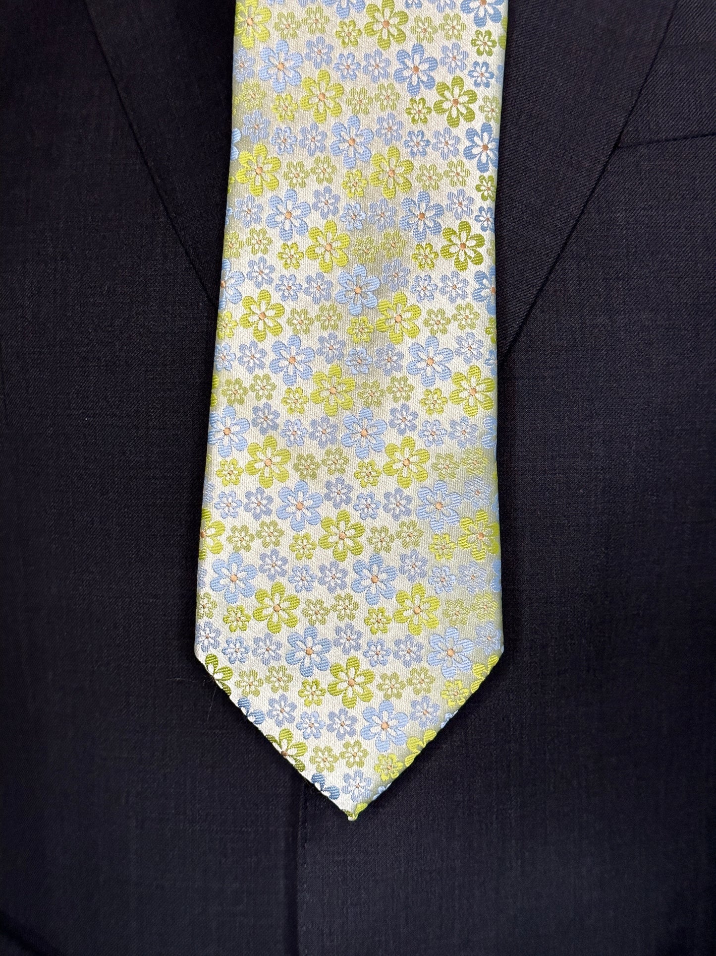 An amazing bright silk woven tie with summer mini florets. The characteristics of this tie coloration are very interesting in that it tends to take on the colors of what it is paired with. Take for instance the solid charcoal grey suit in the photos. This tie works very well with it. It would also go well with tan, black, navy, pinstripes, plaids and many others. There are always a few ties each season that tend to go with most colors and patterns and this is one of them.