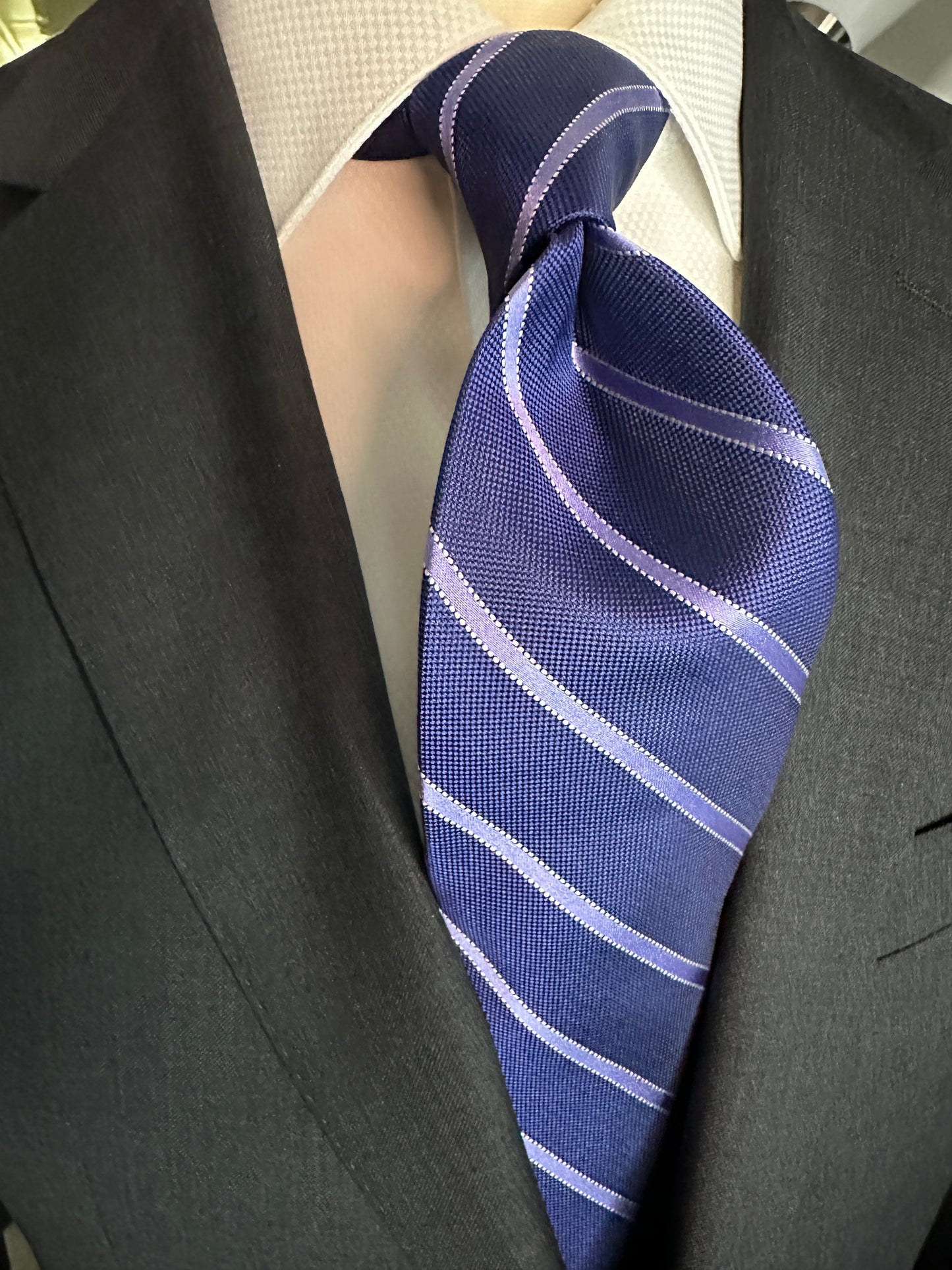 This 100% silk necktie in ink blue with lavender stripe is a very sophisticated Italian tie to be worn with suits or sports jackets. This tie can be very formal with a charcoal grey or navy suit in a classic sense or can be a more casual look with a plaid jacket, light grey trousers and brown suede loafers. 